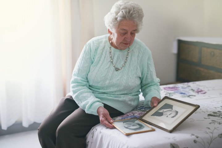 senior woman looking at photographs | Featured image of the How to Plan a Meaningful Cremation Memorial Service blog