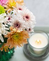 Flowers beside a candle in quiet tribute to a loved one.